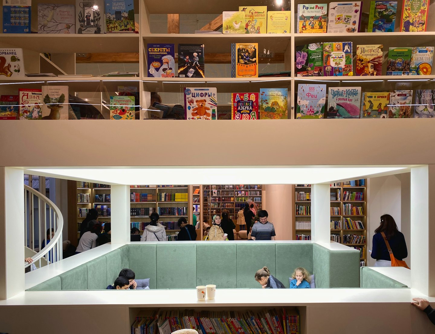 Klanten snuffelen tussen de schappen en lezen in een moderne boekwinkel met meerdere verdiepingen.