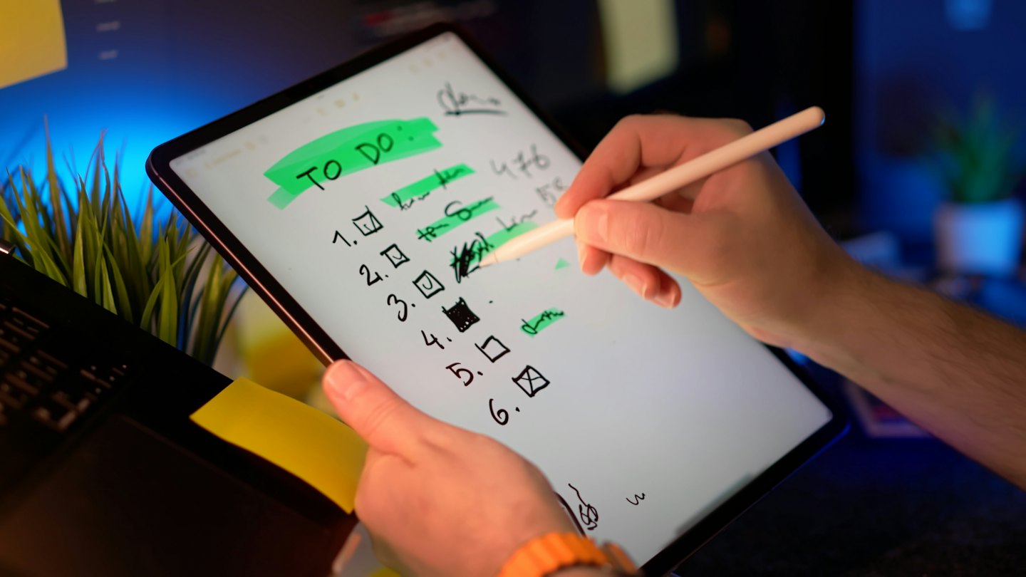 Handen gebruiken een stylus om een digitale takenlijst af te vinken.