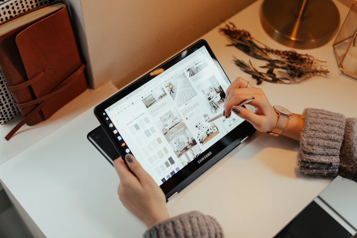 Handen die een tablet gebruiken op een wit bureau met decoratie-inspiratie.