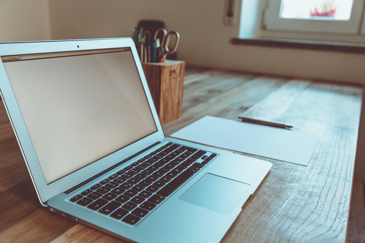 Laptop en kantoorbenodigdheden op een houten bureau.