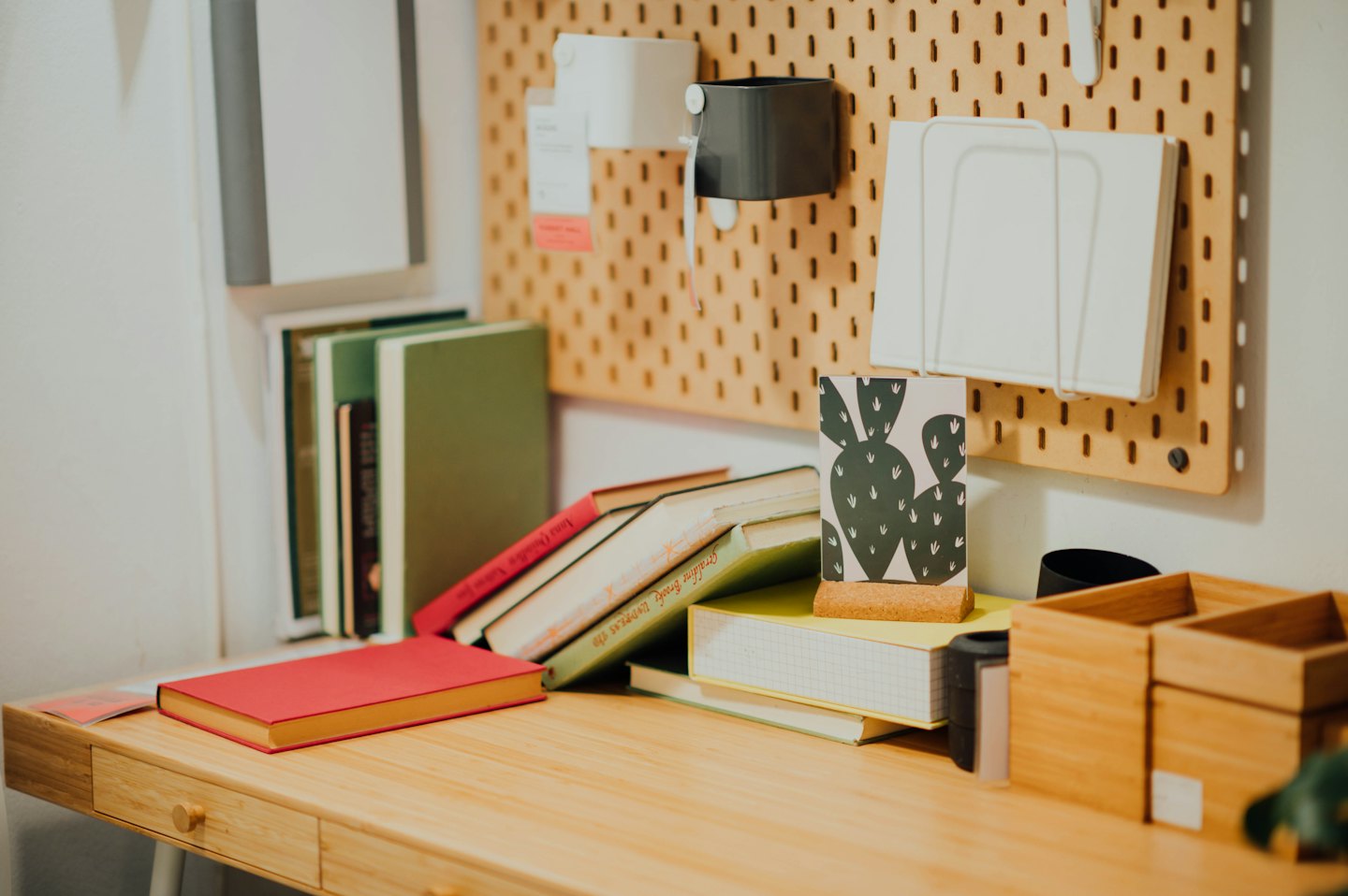 Boeken en kantoorbenodigdheden liggen op een houten bureau.